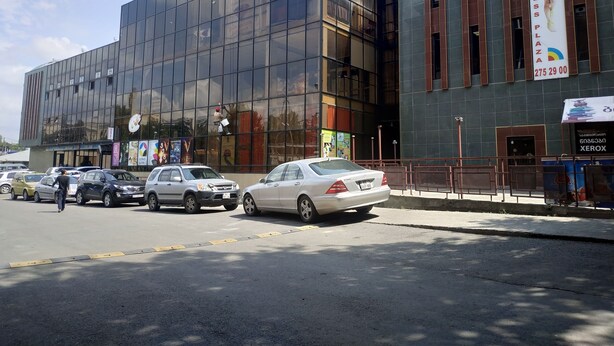A modern building with large glass windows and a sign advertising a fitness place. - Hostel Portal (Tbilisi)