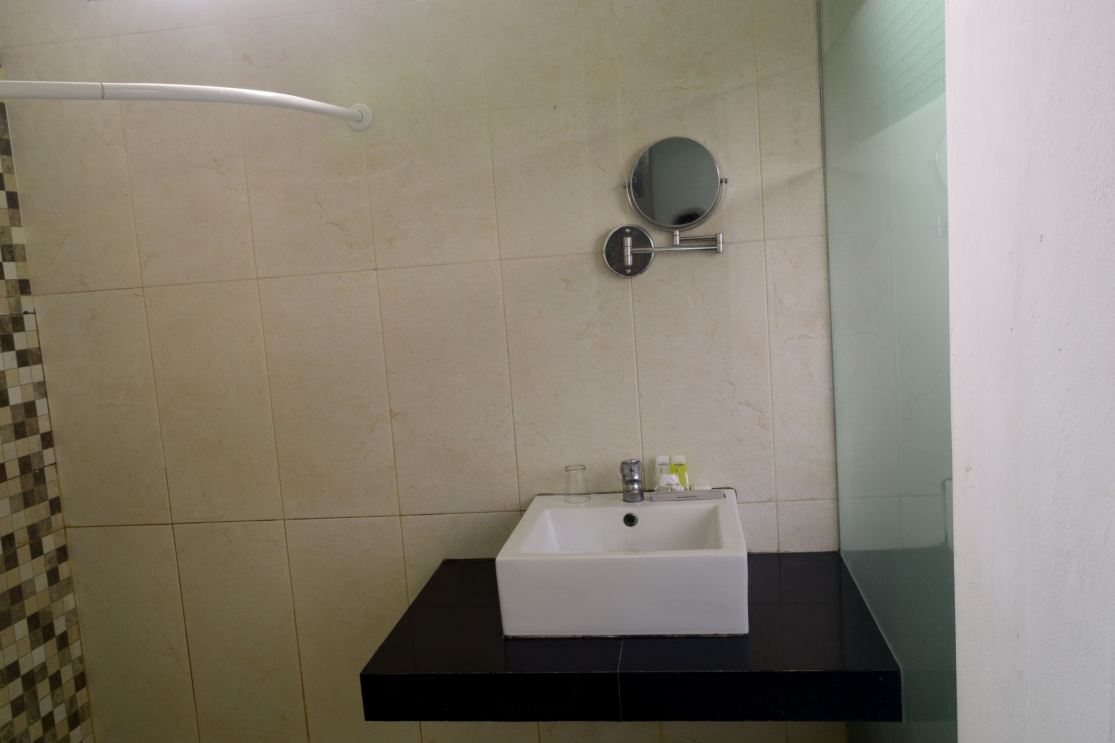 Un baño con lavamanos blanco, un espejo y un perchero para toallas.