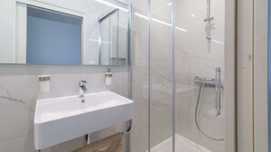 Een moderne badkamer met een witte wastafel, een spiegel en een douchecabine met glazen wanden.