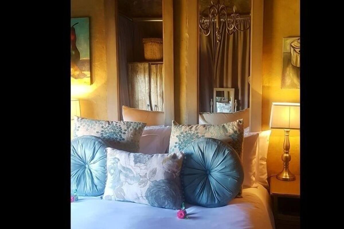 Un lit avec plusieurs oreillers et une table de chevet avec une lampe.
