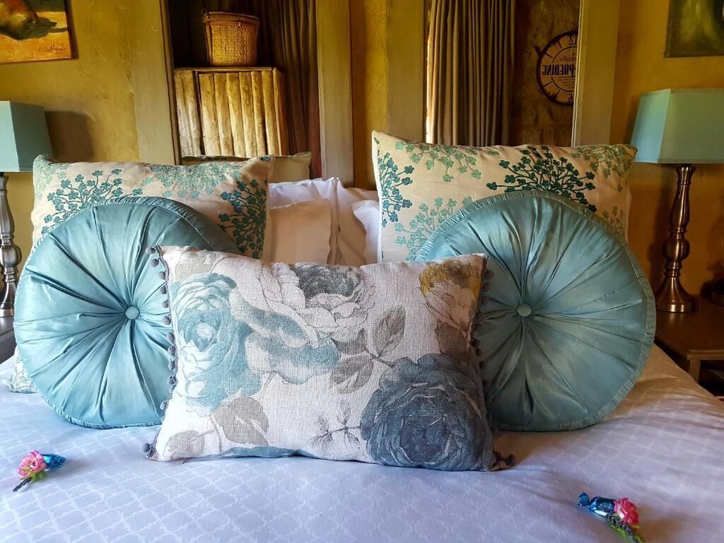 A bed with multiple pillows, a bedside table, and a lamp.