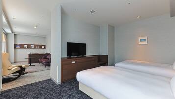 A hotel room with a bed, a TV, a desk, and a chair.