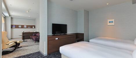A hotel room with a bed, a TV, a desk, and a chair.