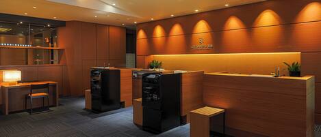 Et moderne receptionområde med en træreception, et loungeområde og en automt.