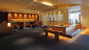 A modern hotel lobby with a reception desk, seating area, and a decorative wall with circular patterns. - JR KYUSHU HOTEL Miyazaki (Miyazaki)