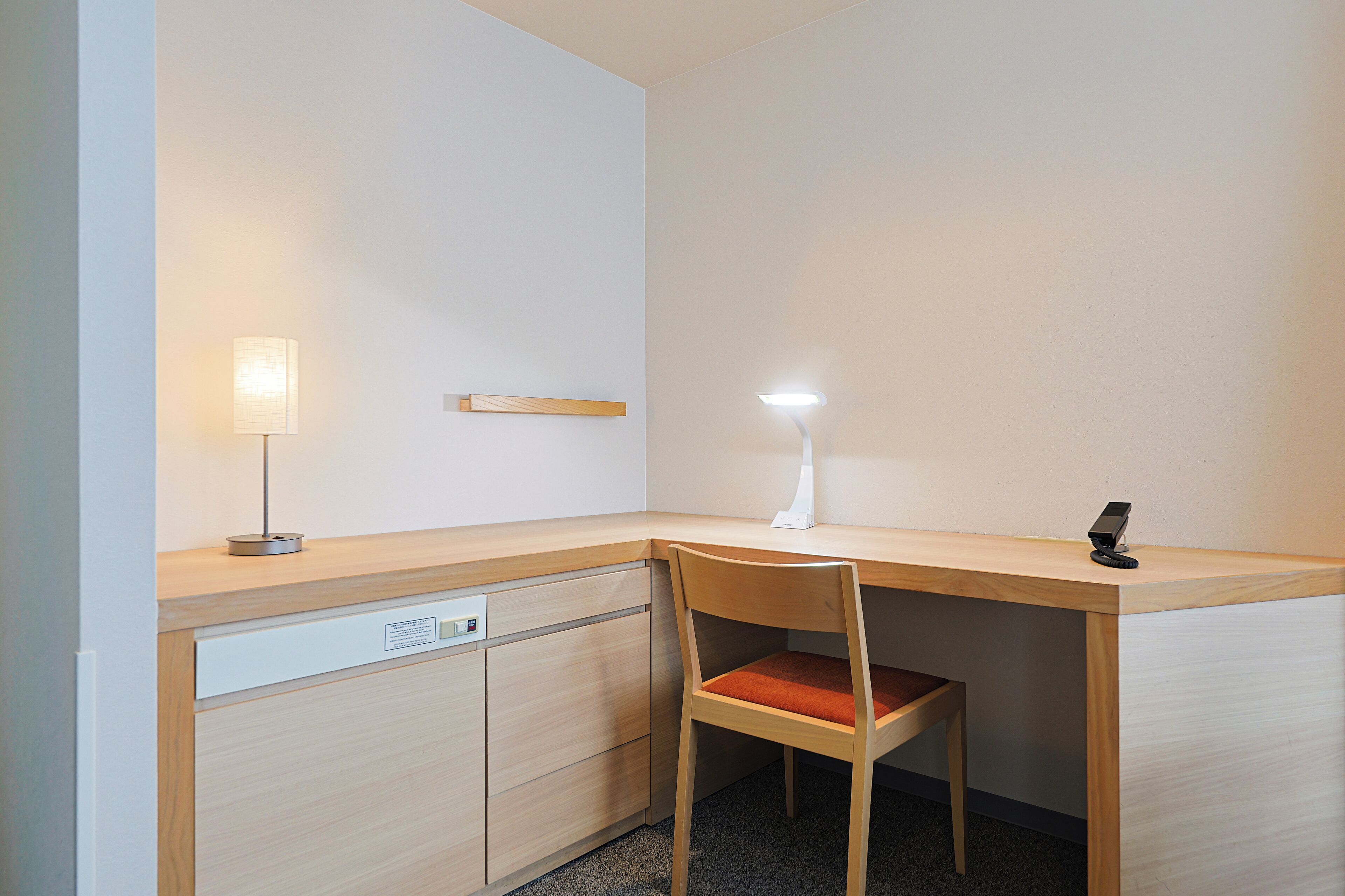 A corner desk with a chair, a lamp, and a phone.