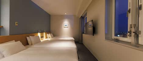 A hotel room with a large bed, a TV, and a window with a view of the city at night.
