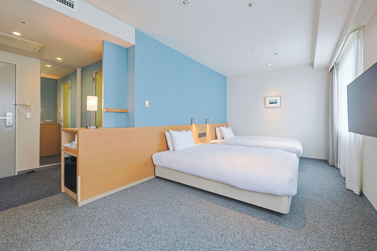 Une chambre d’hôtel avec un grand lit, un bureau en bois, un miroir et une télévision.