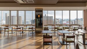 A spacious dining area with large windows offering a city view, wooden tables and chairs, and a modern ceiling design. - JR KYUSHU HOTEL Miyazaki (Miyazaki)
