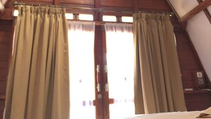A room with a sloped ceiling, wooden beams, and a bed with a white mattress. - Raffles Inn Labuan Bajo (Labuan Bajo)