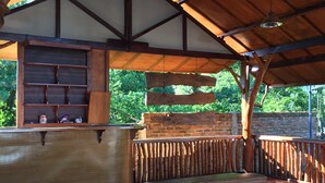 An outdoor wooden deck with a rustic design, featuring a built-in bench and a shelf unit. - Raffles Inn Labuan Bajo (Labuan Bajo)