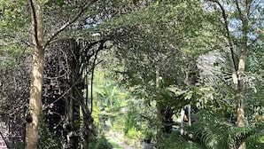 A stone pathway flanked by potted plants and trees, leading to a bench area. - Raffles Inn Labuan Bajo (Labuan Bajo)