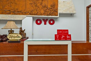 A reception desk with a lamp, a 'Reception' sign, and a 'OYO' sign above it.