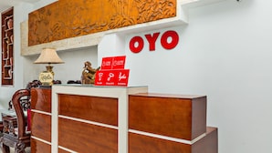 A reception desk with a wooden finish, a large 'OYO' sign, a lamp, and a decorative piece. - Loan Anh 2 Hotel (Da Nang)
