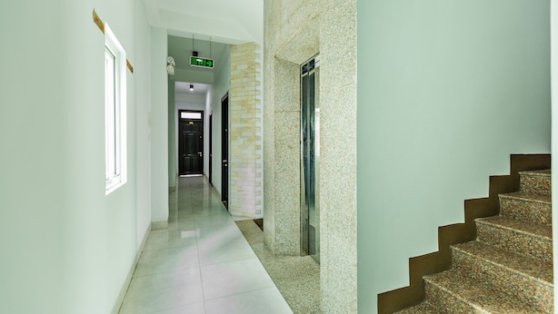 A hotel hallway with a staircase, a wall-mounted exit sign, and a door. - Loan Anh 2 Hotel (Da Nang)
