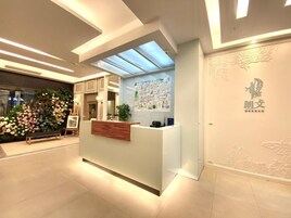 Un mostrador de recepción con panel de madera, vitrina de cristal y pared con motivos florales.