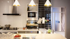 A modern kitchen with a central island, built-in oven, microwave, and stainless steel range hood. - Lanven Art House (Hualien City)