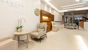 A modern hotel lobby with a reception desk, seating area, and a decorative wall with the name 'LANVEN HOME STAY'. - Lanven Art House (Hualien City)