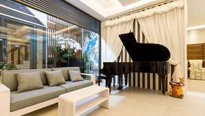 A modern living room with a grand piano, a sofa, and a coffee table. - Lanven Art House (Hualien City)