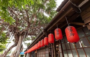 A traditional building with a large tree in front and red lanterns hanging on the side. - Lanven Art House (Hualien City)