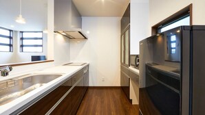 Una cocina moderna con un lavamanos de acero inoxidable, un refrigerador negro y piso de madera.