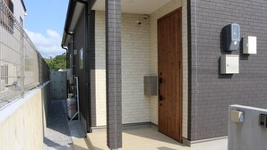 Un edificio moderno con fachada de ladrillo, puerta de madera y cámara de seguridad.
