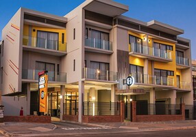 Un hotel de varios pisos con balcones, un letrero llamativo y una entrada con portón.