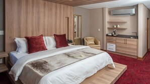 A modern hotel room with a large bed, a desk, and a kitchenette. - Loch Logan Hotel (Bloemfontein)