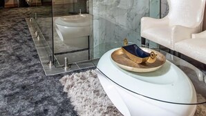 A modern interior with a glass partition, a white sofa, a chandelier, and a marble wall. - Loch Logan Hotel (Bloemfontein)