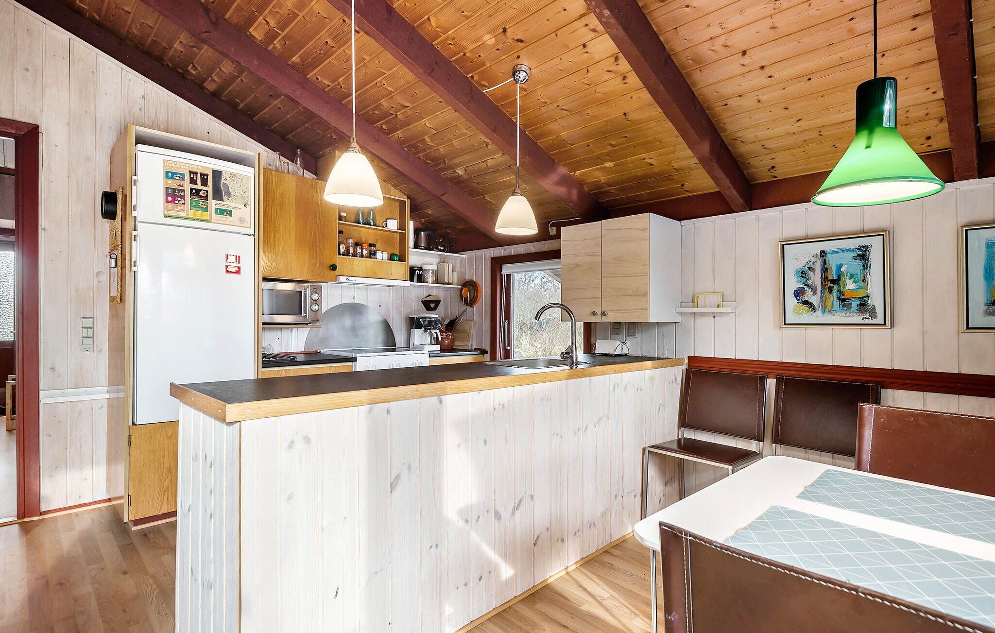 Een keuken met houten kastjes, een centraal eiland en hangende lampen.