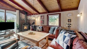 Ein gemütliches Wohnzimmer mit Kamin, Ledersofa, Holztisch und Fernseher.