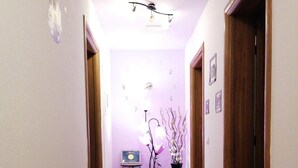 A hallway with a tiled floor, a ceiling light fixture, and a small table with a vase of flowers. - Guest House Macic (Plitvicka Jezera)