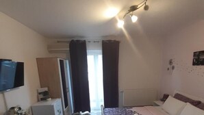 A hotel room with a bed, a desk, a chair, a television, and a window with curtains. - Guest House Macic (Plitvicka Jezera)