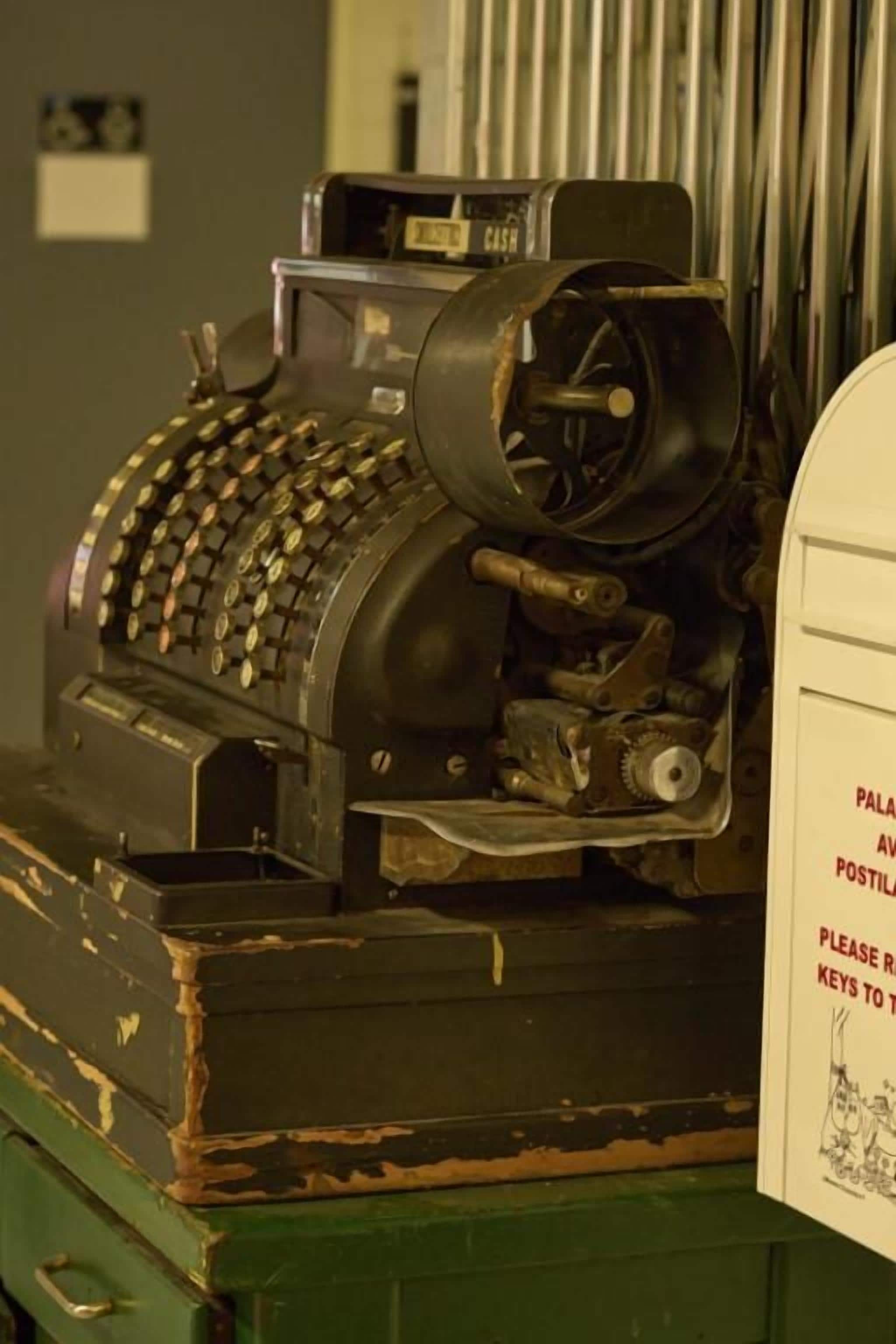 A vintage cash register with a green base, placed on a wooden surface.