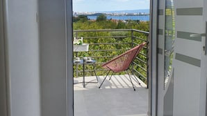 A room with a sliding glass door leading to an outdoor balcony with a chair and table. - Apartments Cingulice (Kastela)