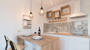 A modern kitchen with a wooden island, white cabinets, and patterned backsplash tiles. - Apartments Cingulice (Kastela)