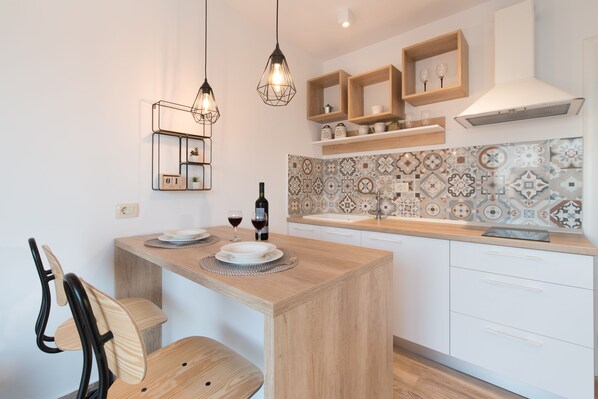 Une cuisine moderne avec un îlot central en bois, des armoires blanches et des carreaux décoratifs sur le mur derrière l’évier.