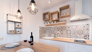A modern kitchen with a wooden countertop, white cabinets, a patterned backsplash, and pendant lighting. - Apartments Cingulice (Kastela)