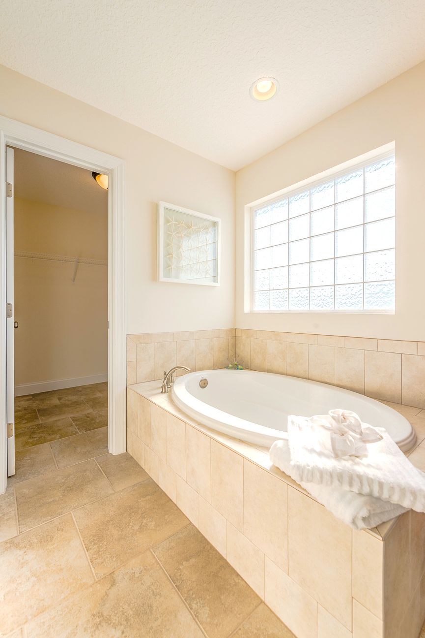 Un bagno con una vasca da bagno indipendente, una finestra con un motivo a griglia e un accesso a un angolo doccia.