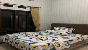 A bedroom with a bed, curtains, an air conditioning unit, and a window. - Green Homestay (Batu)