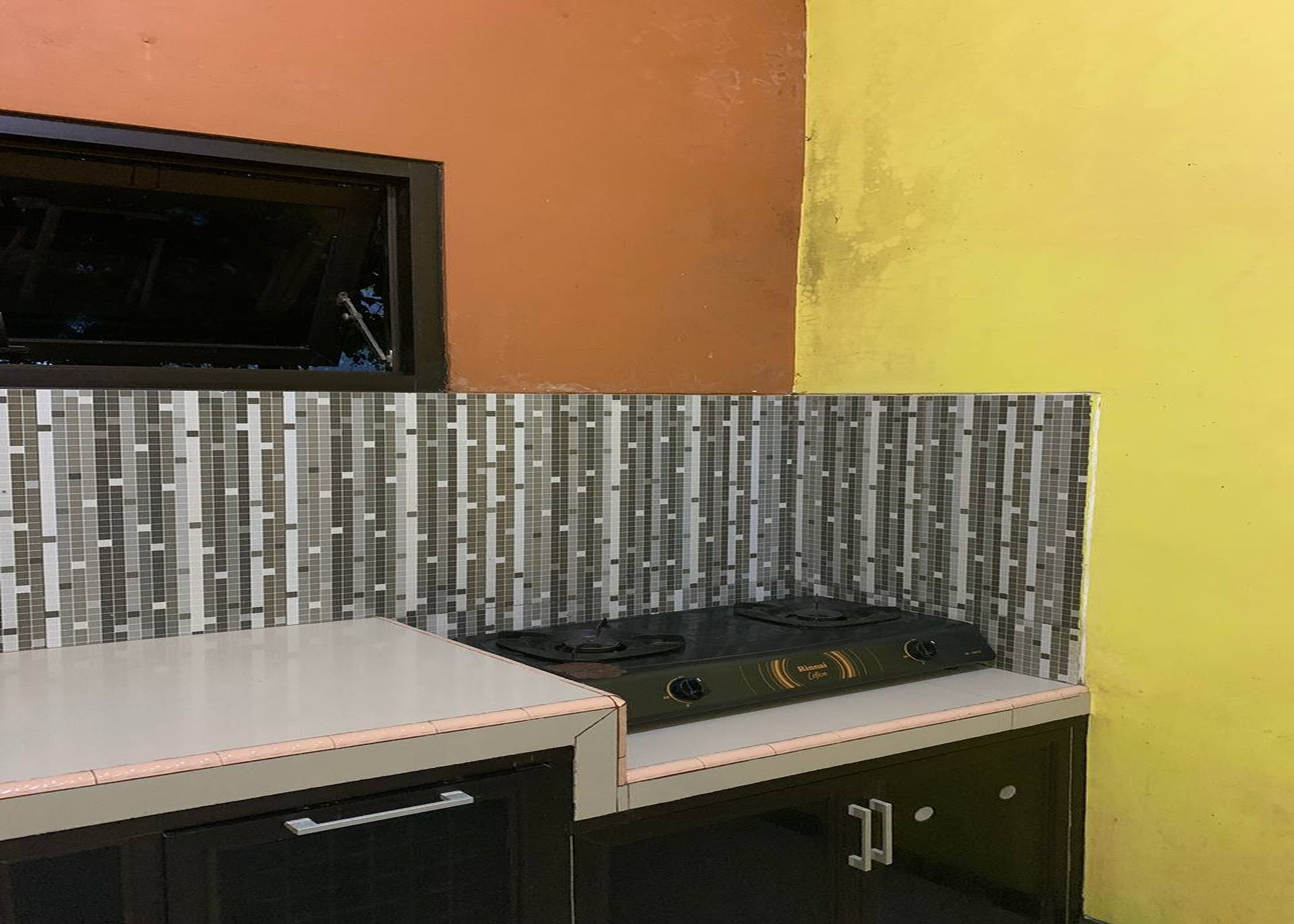 Una cocina con salpicadero de azulejos, estufa y armarios.