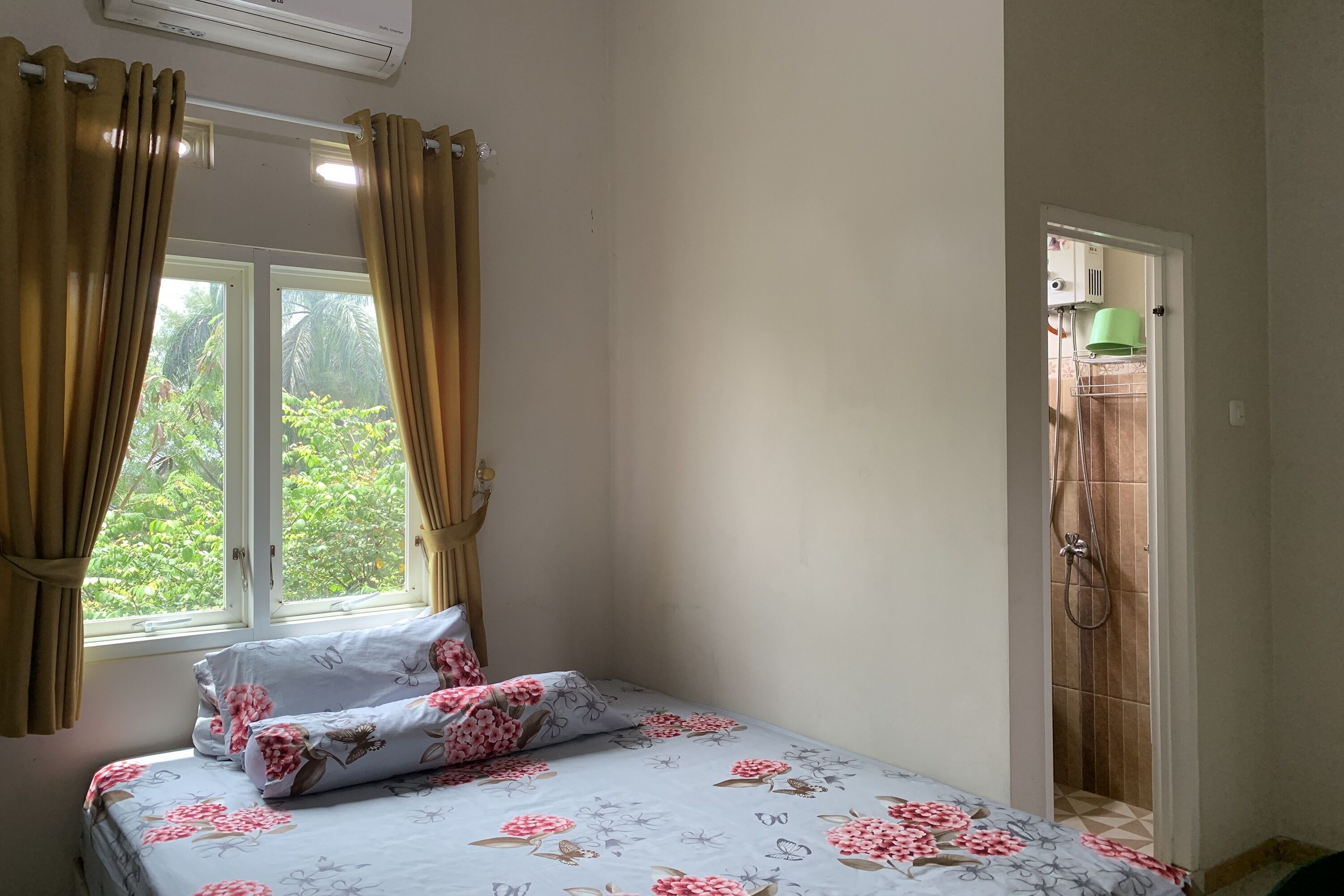 A bedroom with a bed, curtains, a window, and a shower area.
