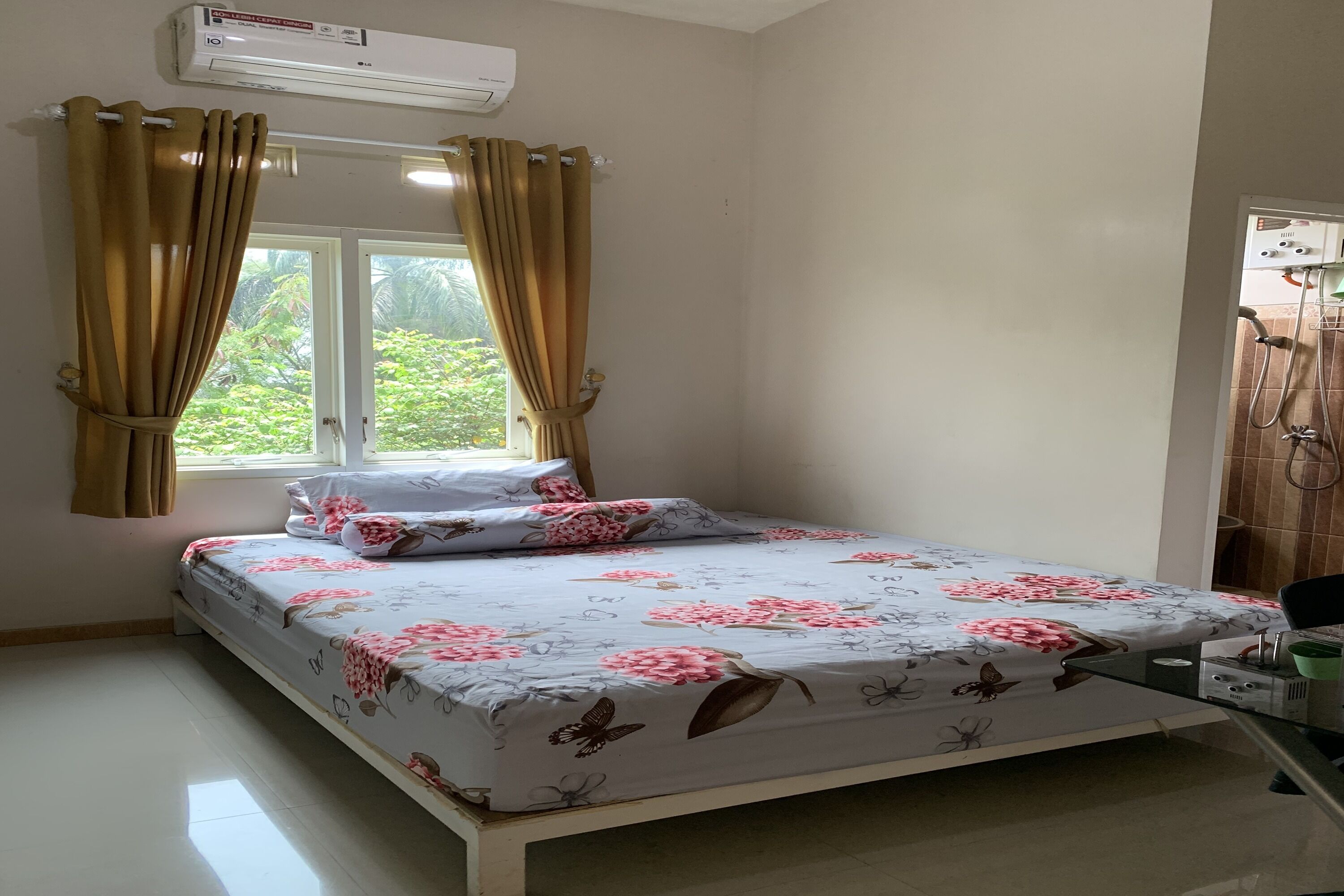 Une chambre à coucher avec un lit, des rideaux, un climatiseur et une fenêtre donnant sur un paysage verdoyant.