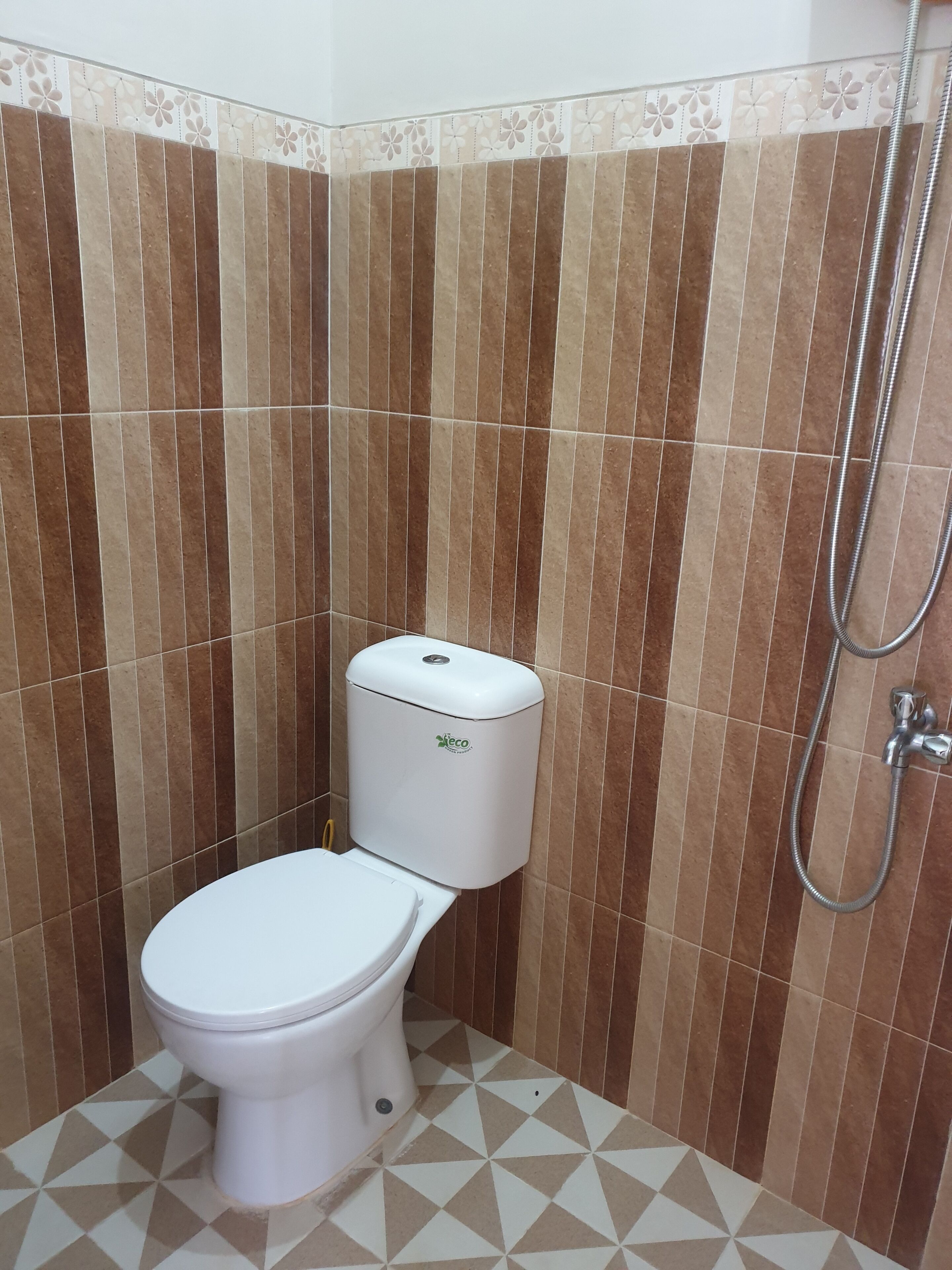 Un baño con inodoro, ducha y azulejos estampados.