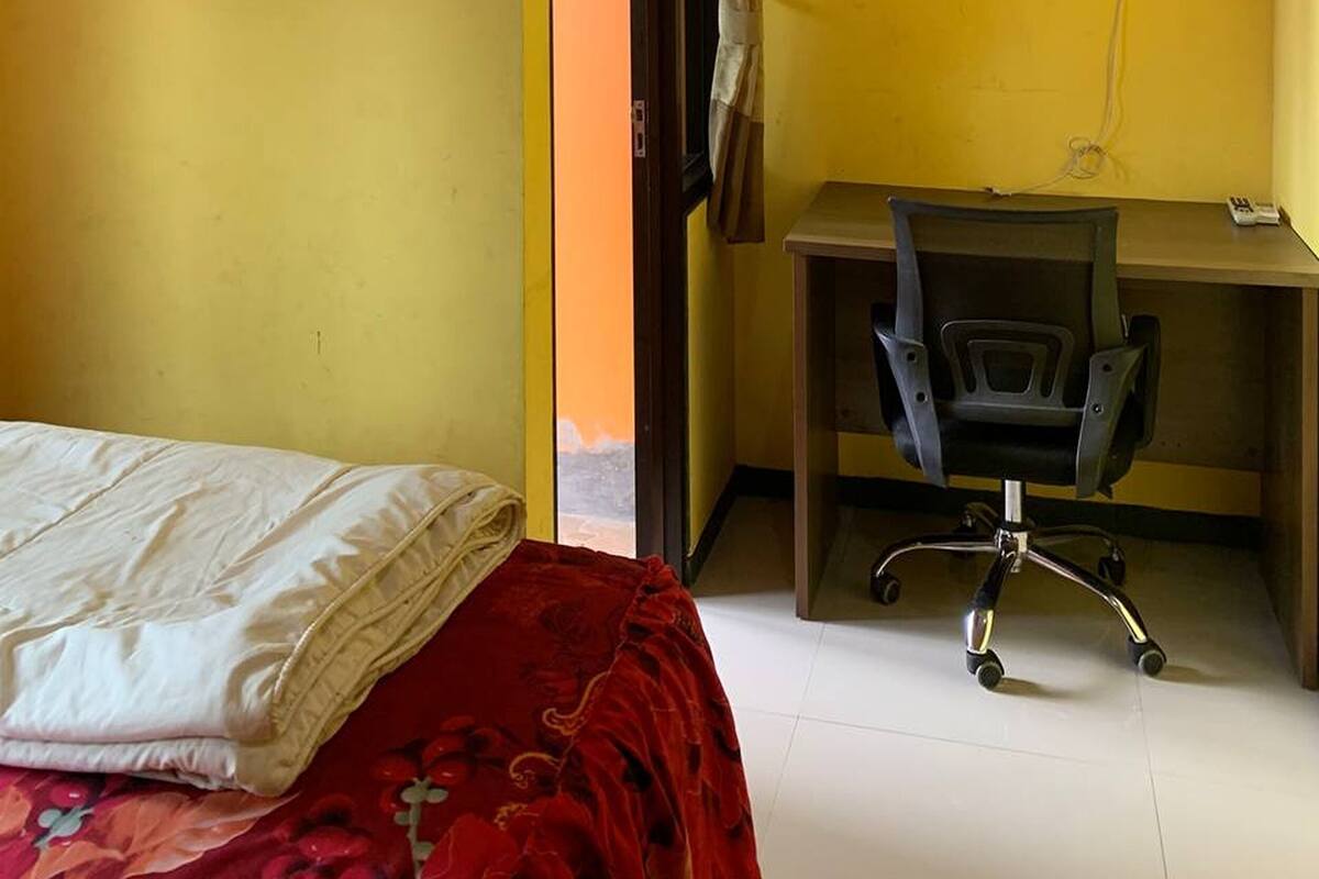 Ein Zimmer mit einem Bett, einem Schreibtisch mit Stuhl, einem Fernseher und einem Vorhang.