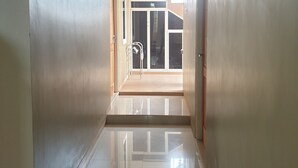 A hallway with a glossy floor, leading to a door with a glass panel. - Green Homestay (Batu)