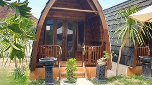A wooden cabin with a triangular roof, a porch with wooden railings, and potted plants. - Jambu Guesthouse (Penida Island)