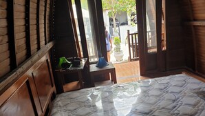 Una habitación con una cama grande, paredes de madera, una mesita con una lámpara y vistas al exterior.