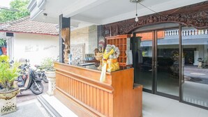 A reception desk with a statue, a motorcycle, and a potted plant. - Mahendra Beach Inn (Kuta)