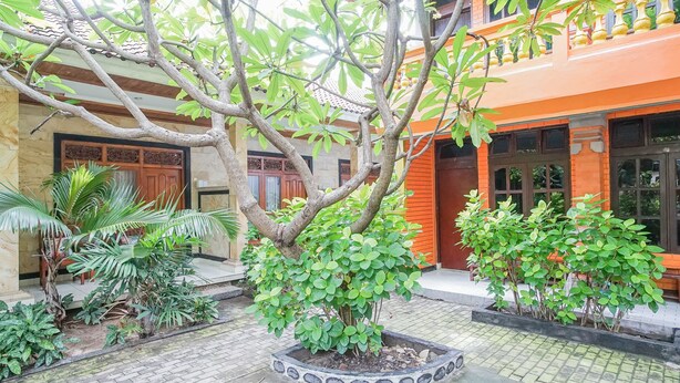 A courtyard with a central tree, potted plants, and a tiled floor. - Mahendra Beach Inn (Kuta)